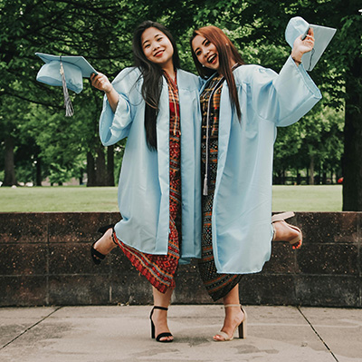 Two spring graduates in light blue gowns